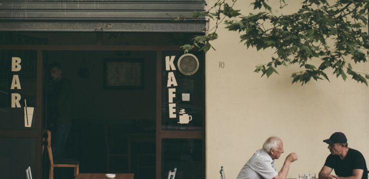 two men sitting outside of a cafe